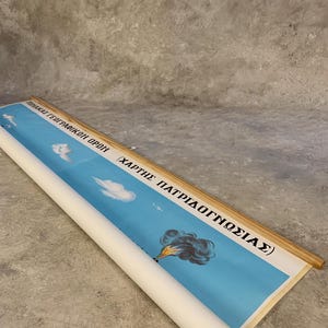 May include: Rolled vintage educational chart with a blue sky background, featuring clouds, an airplane, and a depiction of a fire. The chart has text in Greek and is mounted on wooden dowels.