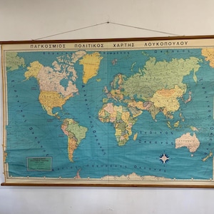 Puede incluir: Un mapa político mundial vintage con un fondo oceánico azul y continentes coloridos. El mapa está montado sobre varillas de madera y presenta texto griego en la parte superior. El mapa muestra los países y océanos del mundo.