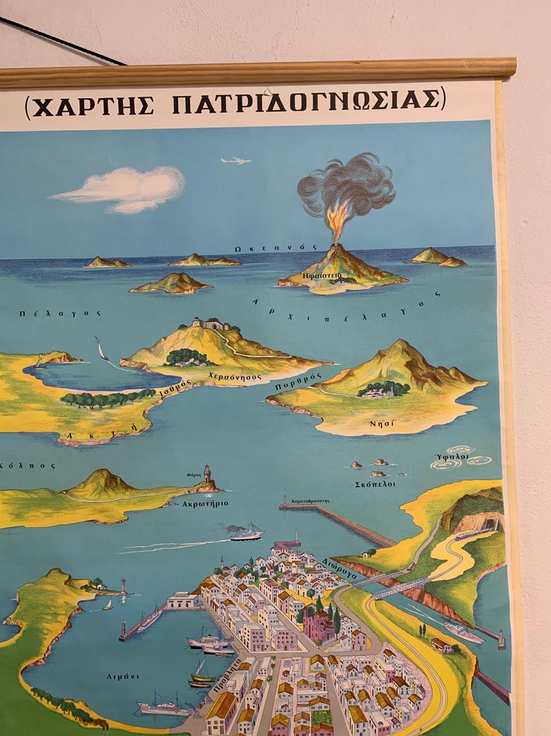 May include: Vintage educational map featuring a detailed illustration of an island landscape with a volcano, islands, and a coastal town. The map includes Greek text and is mounted on wooden rods.