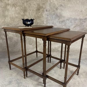 Puede incluir: Un conjunto de tres mesas nido de madera oscura con un diseño simple y elegante. Las mesas tienen una tapa rectangular y patas delgadas.