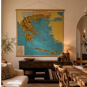 Puede incluir: Un gran mapa de pared de Grecia con masas terrestres amarillas y mar azul, suspendido por varillas de madera. El mapa muestra el texto "ΧΑΡΤΗΣ ΤΗΣ ΕΛΛΑΔΟΣ" en la parte superior, con marcas topográficas detalladas y una leyenda en la esquina inferior izquierda.