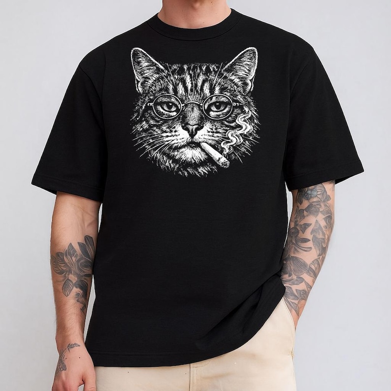 May include: Black t-shirt with a detailed monochrome illustration of a cat wearing round spectacles and smoking a cigarette. The cat's face is the central image, with smoke curling from the cigarette.