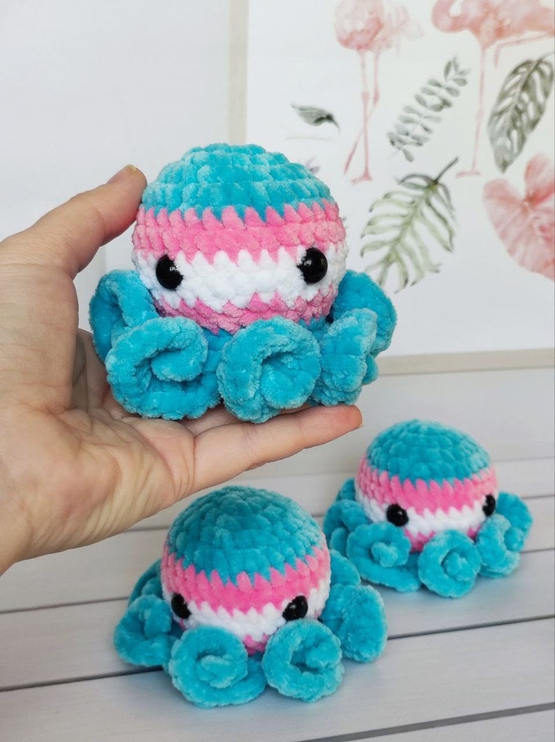 May include: Three crocheted octopus plushies with blue, pink, and white yarn. The octopus plushies have black eyes and are arranged on a white surface.
