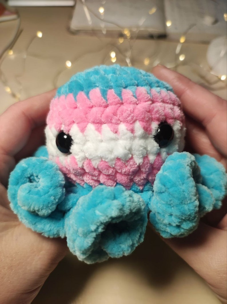 May include: A crocheted octopus plush toy with blue, pink, and white yarn. The octopus has large black eyes and a curled tentacle.
