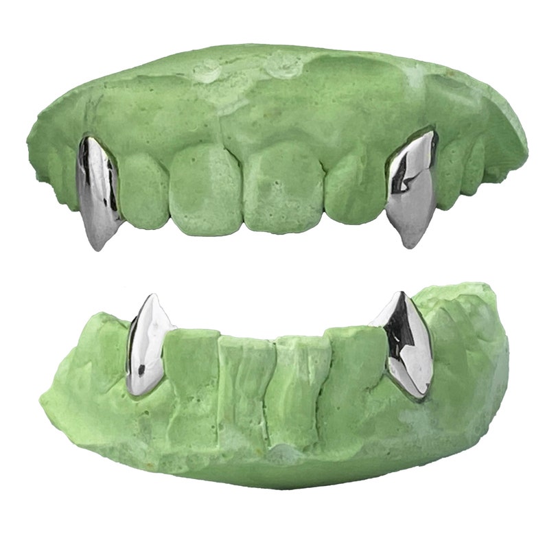 Puede incluir: Un juego de dos dientes de vampiro de pl&aacute;stico verde con colmillos de metal plateado. Los dientes est&aacute;n dise&ntilde;ados para colocarse sobre los dientes existentes.
