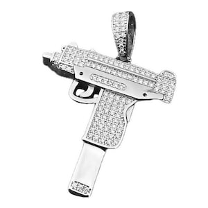 May include: A silver-toned pendant in the shape of a handgun, completely covered in clear cubic zirconia stones.