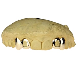May include: Gold teeth grill with two front teeth, set in a mold.
