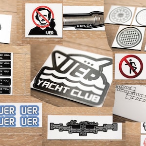 May include: A collection of stickers featuring various designs, including a boat with the text "UER Yacht Club", a man with a no smoking sign, and a man with the text "UER". There are also stickers with the text "UER" and "Nice to see you, UER.CA" repeated multiple times.