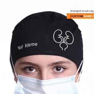 May include: Black urologist scrub cap with white embroidered kidney and bladder graphic. The cap has the text "Your Name" and "CUSTOM NAME AVAILABLE". The person is wearing a surgical mask.