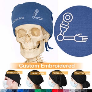 May include: A blue surgical scrub cap with white embroidered design and the text "Custom text". The cap is shown on a human skull. Additional scrub caps in black are shown below the skull.