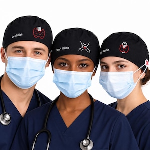 May include: Three black scrub caps featuring embroidered medical graphics and customisable text. The caps display white and red thyroid or anatomical icons, with text reading Dr. Smith or Your Name, worn with light blue surgical masks and stethoscopes.