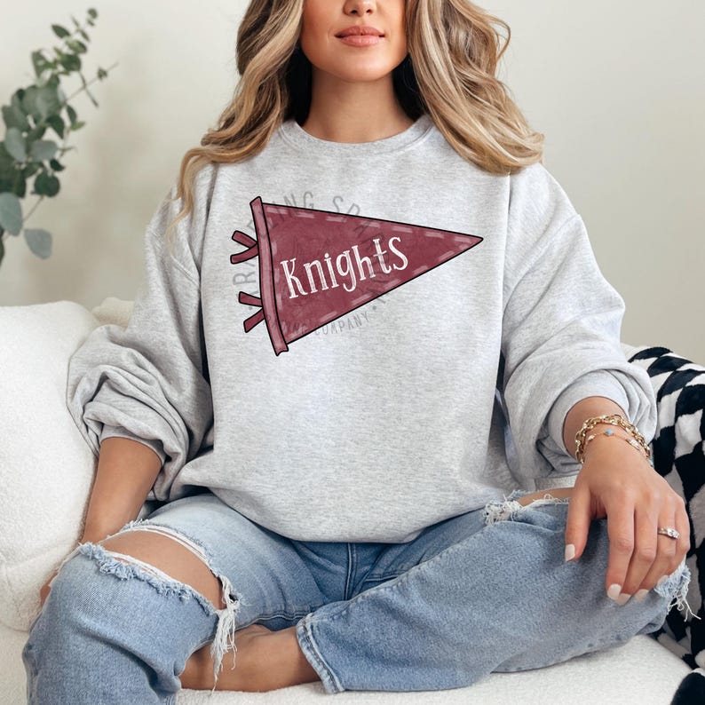 Pode incluir: Um moletom cinza claro com uma fl&acirc;mula bord&ocirc; com a palavra "Knights" em branco. A fl&acirc;mula tem um design vintage. O moletom &eacute; um estilo de gola redonda.