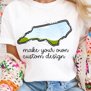 May include: White t-shirt with a black outline of the state of North Carolina and the text "make your own custom design".