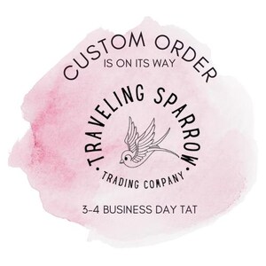 May include: A pink watercolor background with the text "CUSTOM ORDER IS ON ITS WAY" in a circle. Below the circle is the text "TRAVELLING SPARROW TRADING COMPANY" in a circle with a stylized sparrow illustration. The text "3-4 BUSINESS DAY TAT" is below the circle.