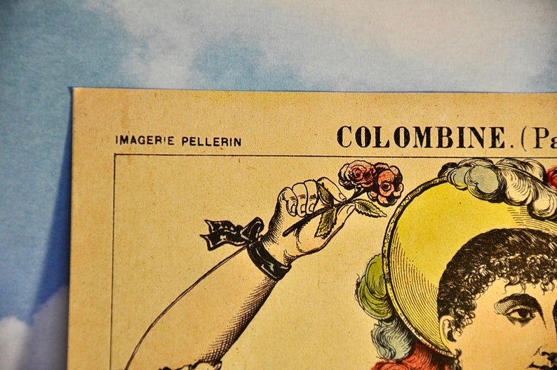 May include: A vintage-style paper print featuring the text IMAGERIE PELLERIN and COLOMBINE. The illustration depicts a figure with dark curly hair wearing a yellow hat with feathers, holding a small stem with pink roses in a raised hand.