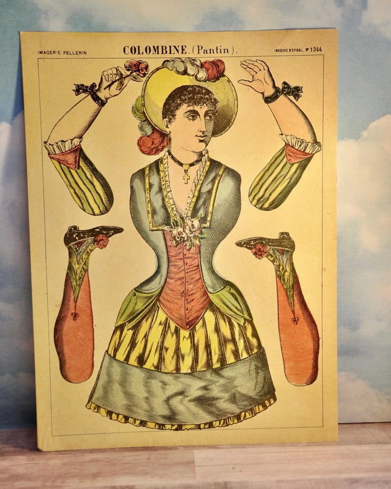 May include: A vintage paper doll sheet titled COLOMBINE (Pantin) featuring a central figure with a yellow hat, blue jacket, and yellow skirt. The sheet includes detached arms and legs with floral accents, printed on cream paper with text.