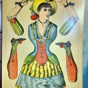 May include: A vintage paper doll sheet titled COLOMBINE (Pantin) featuring a central figure in a blue, red, and yellow dress with a hat, surrounded by detached arms and legs. The illustration includes a cross necklace and floral accents.