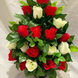 May include: A bouquet of artificial roses in a black pot. The roses are a mix of red and white.