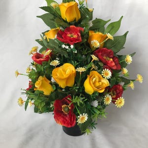 May include: A yellow and red artificial flower arrangement in a black pot. The arrangement features yellow roses, red poppies, and white daisies.