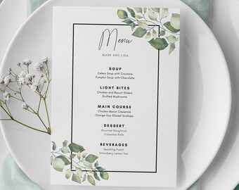 May include: A white card with a black border and green watercolor leaves on the right side. The card has the word "Menu" written in cursive at the top and the names "Mark and Lisa" written below. The menu lists the following items: Soup, Light Bites, Main Course, Dessert, and Beverages.