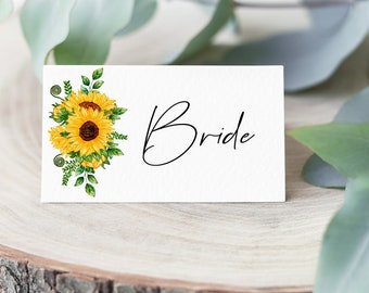 May include: A white place card with a sunflower bouquet illustration and the word "Bride" written in black cursive.