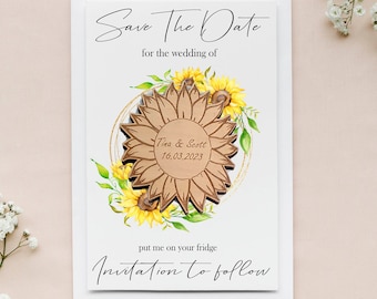 May include: Save the date card with a wooden sunflower design. The card is white with black text that reads "Save the Date for the wedding of Tina & Scott 16.03.2023". The text "put me on your fridge" and "Invitation to follow" are also included.