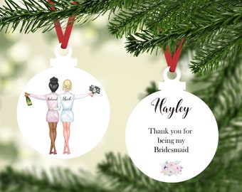 May include: Two white round Christmas ornaments with red ribbon hangers. One ornament features a bride and bridesmaid in white and pink robes. The other ornament has the name Hayley and the text "Thank you for being my Bridesmaid".