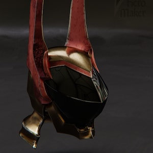 Könnte beinhalten: Ein futuristischer Helm mit schwarzem Visier und roten und goldenen Akzenten. Der Helm hat zwei große, spitze Hörner.