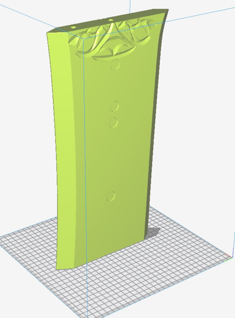 May include: A light green, stylized, rectangular object with a decorative floral design at the top and three circular indentations. The object is standing upright on a grid.