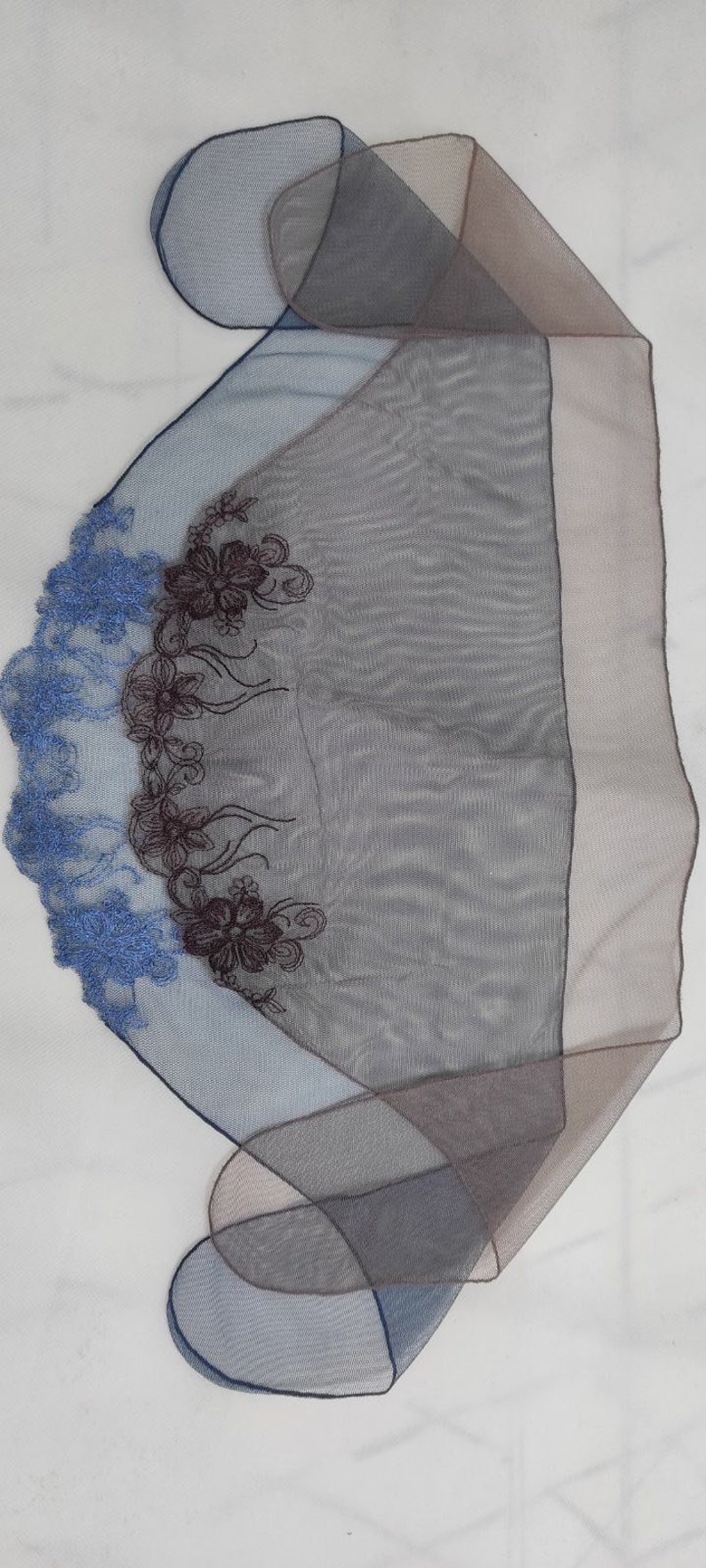 Puede incluir: Una bufanda azul y marr&oacute;n transparente con bordado floral. El bordado es en tonos azules y marrones.