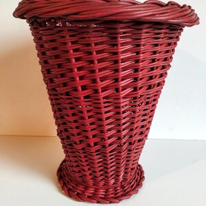 Peut inclure: Un panier rouge tressé de forme évasée. Le panier a une base arrondie et un bord tressé. Le motif de tissage est serré et régulier, créant une surface texturée. Le panier est fait d'un matériau robuste.