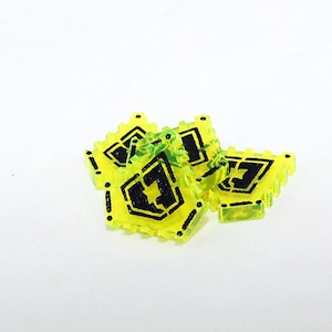 May include: Four yellow plastic game pieces with black markings. Each piece has a different design, including a shield with a letter T inside.