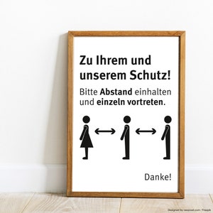 May include: A white sign with black text and stick figures. The sign reads "Zu Ihrem und unserem Schutz! Bitte Abstand einhalten und einzeln vortreten. Danke!"