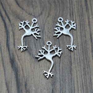 May include: Three silver charm pendants shaped like a neuron, a type of nerve cell. The charms are detailed with intricate branches and a central body.
