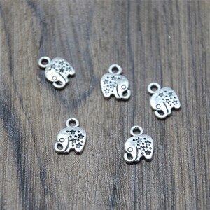 Può includere: Cinque ciondoli in argento a forma di elefante con un motivo a stella. I ciondoli hanno un anello nella parte superiore per essere attaccati a una collana o un braccialetto.