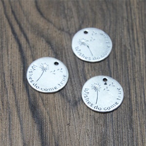 May include: Three silver round charms with a dandelion design and the text "Wishes do come true".