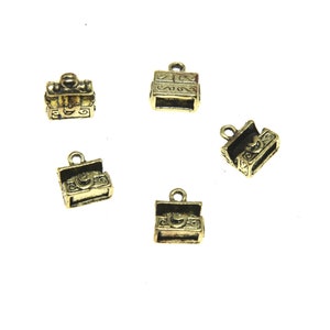 May include: Five gold-tone metal charms shaped like treasure chests with ornate details. The charms have a loop at the top for attaching to a necklace or bracelet.