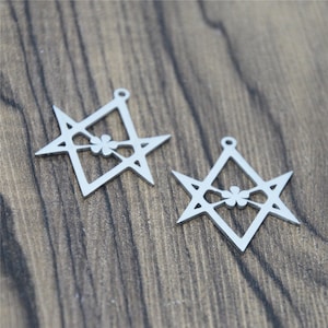 Könnte beinhalten: Zwei silberne Metallanhänger in Form eines sechszackigen Sterns mit einem vierblättrigen Kleeblatt in der Mitte.