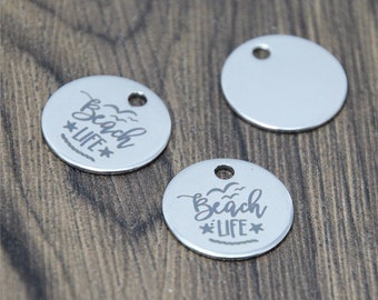 May include: Three silver metal round charms with a hole at the top. Two charms have the text "Beach Life" with a star and a wave design. One charm is blank.