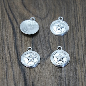 May include: Four silver-toned metal charms, two with a five-pointed star design and two with a smooth, circular surface. The charms have a loop at the top for attaching to jewelry or other crafts.