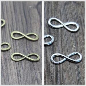 May include: Two rows of infinity symbol charms, one row in antique gold and one row in silver. The charms are on a wooden surface.