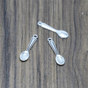 Può includere: Tre ciondoli a forma di cucchiaio d'argento con un design semplice. I cucchiai sono lunghi circa 2,5 cm e hanno una ciotola arrotondata.