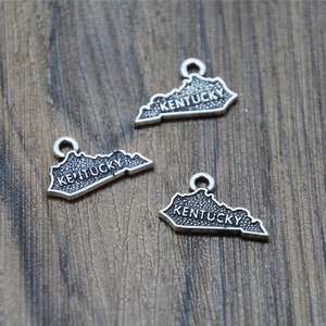 May include: Three silver charm pendants shaped like the state of Kentucky with the word "Kentucky" inscribed on each.