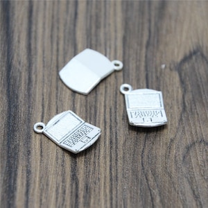 May include: Three silver-toned metal charms shaped like laptop computers. The charms have a detailed design of a laptop screen, keyboard, and trackpad. The charms have a loop at the top for attaching to a necklace or bracelet.