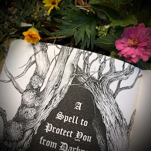 Op de afbeelding: Een zwart-witte illustratie van een boom met takken die een grotachtige opening vormen. De tekst "A Spell to Protect You from Darkness" is geschreven in een gotisch lettertype op een donkere achtergrond.