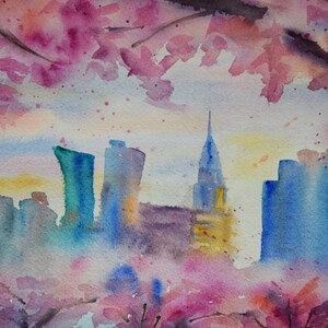 以下が含まれることがあります： ピンクと紫の花が前景に描かれた、都市の水平線の水彩画。都市は青とグレーの色合いで描かれており、中央に高い建物があります。