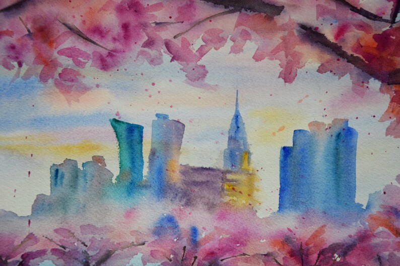 以下が含まれることがあります： ピンクと紫の花が前景に描かれた、都市の水平線の水彩画。都市は青とグレーの色合いで描かれており、中央に高い建物があります。