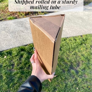 以下が含まれることがあります： 「Shipped rolled in a sturdy mailing tube」という文字が印刷された茶色の段ボール製の郵送用チューブです。