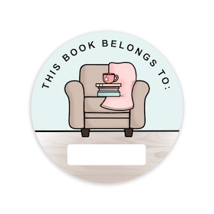 Peut inclure: Un autocollant rond avec un fond bleu clair et un fauteuil marron avec une couverture rose, une pile de livres et une tasse de thé. Le texte "Ce livre appartient à :" est écrit en noir autour du fauteuil. Il y a un espace vide en bas de l'autocollant pour écrire un nom.