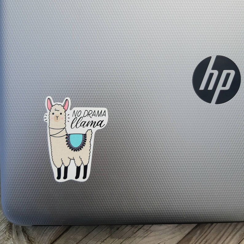 May include: A white llama sticker with a blue and black patterned saddle. The sticker has the text "NO DRAMA llama" on it.